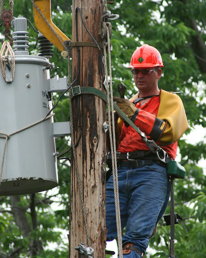 A lineman working on a utility pole transformer
