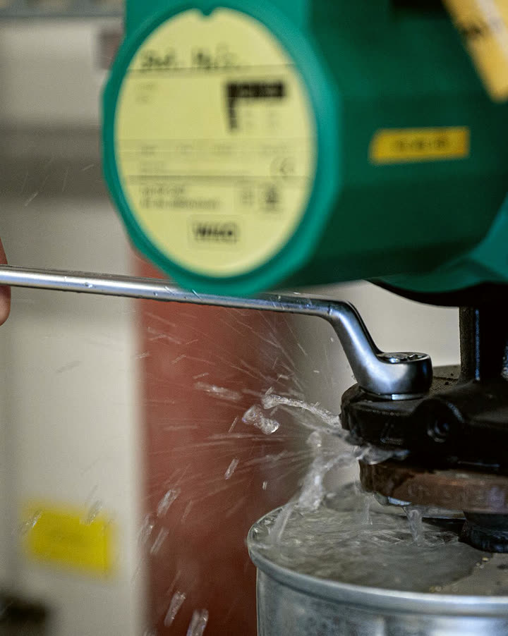 An HVAC tech tightening a fitting with a wrench
